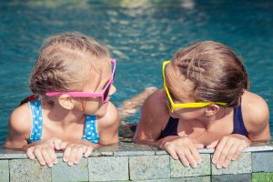 Two happy children  playing on the swimming pool in aqua park at the day time. Concept of friendly family.